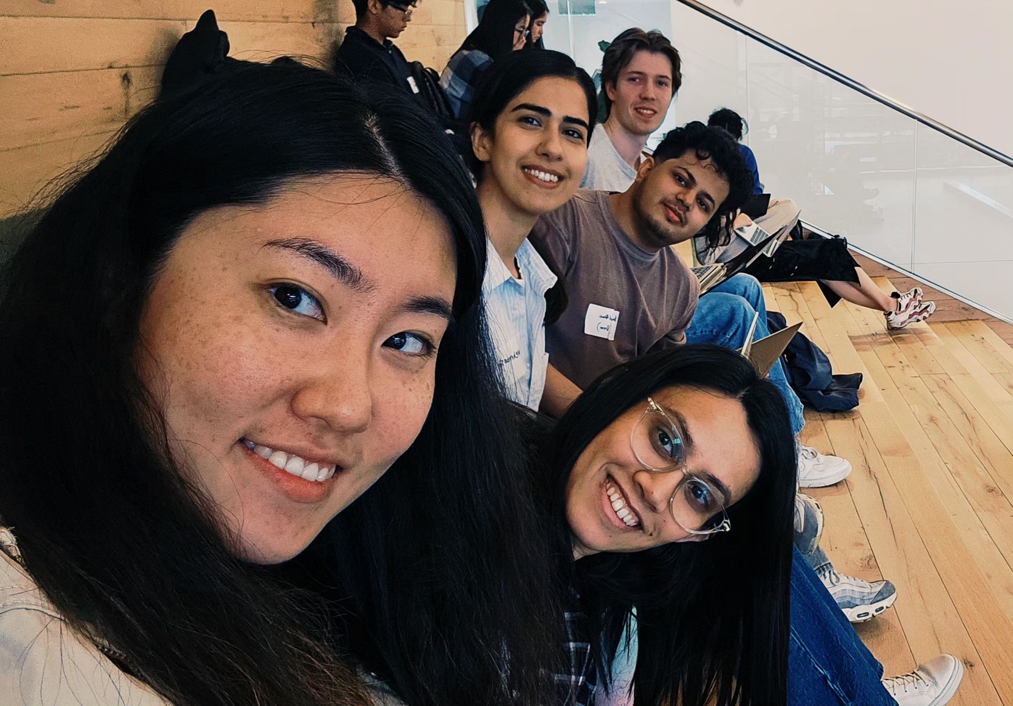Samuel and his hackathon teammates sitting together on a staircase, smiling for the camera.